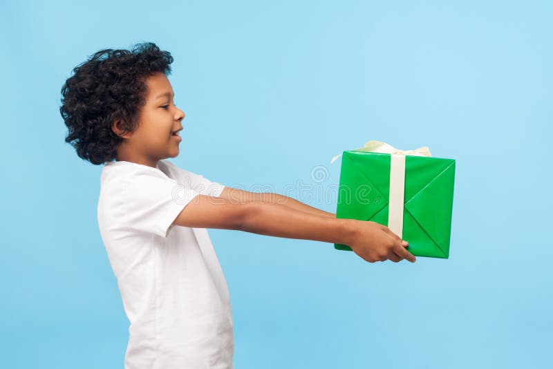 Take this present! Side view of cheerful generous good-natured little boy with curls offering gift box