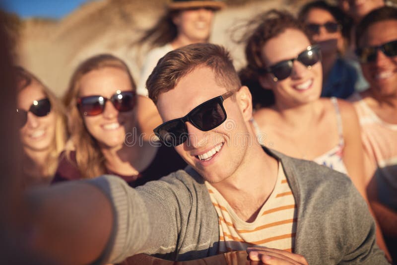 Take a selfie and let the good times roll. Cropped portrait of a handsome young man taking a selfie with his friends at the beach