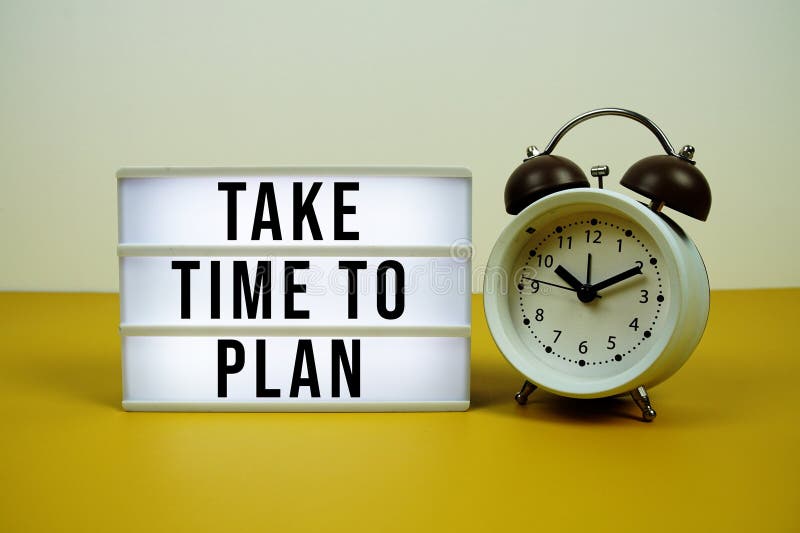 Take Time To Plan text on LED lightbox with alarm clock on yellow background royalty free stock image