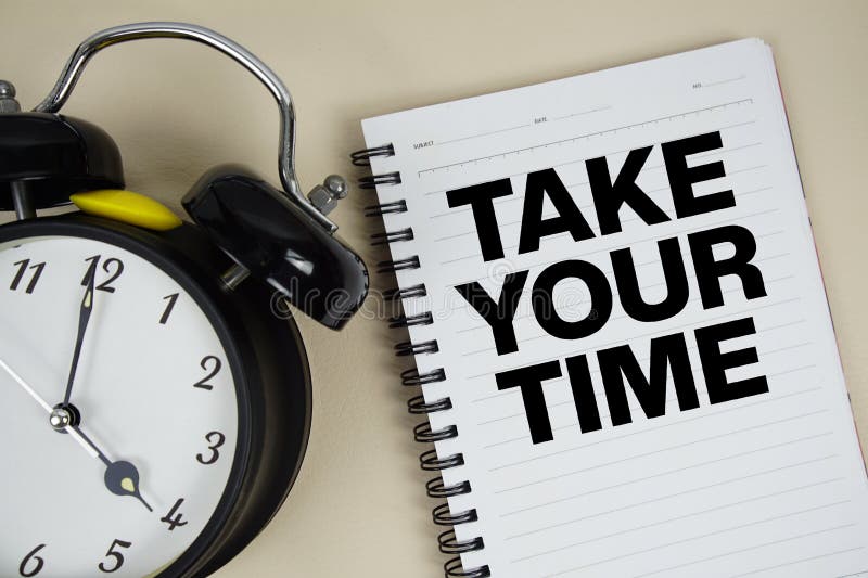 Take Your Time text written on notepad with alarm clock stock image