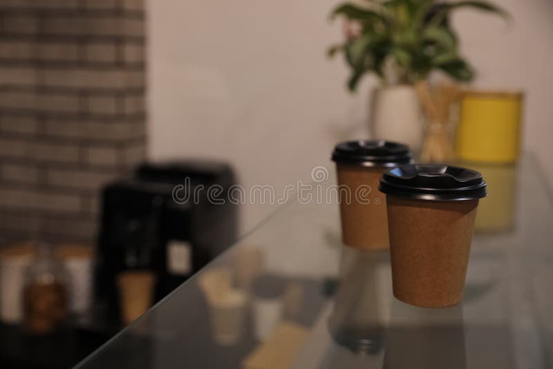 Takeaway coffee cups with plastic lids on glass table in cafe. Space for text royalty free stock photos