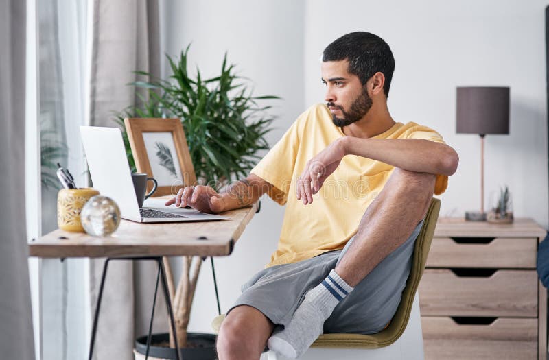 It takes a lot of focus to work from home. a young man using a laptop while working from home. royalty free stock image