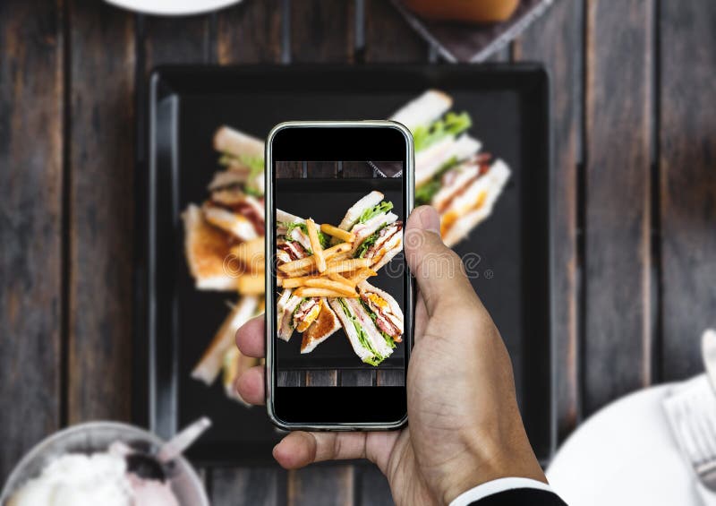 Taking food photo, food photography by smart phone, club sandwich with french fries on wooden table stock photography Taking food photo, food photography by smart phone, club sandwich with french fries on wooden table stock photography