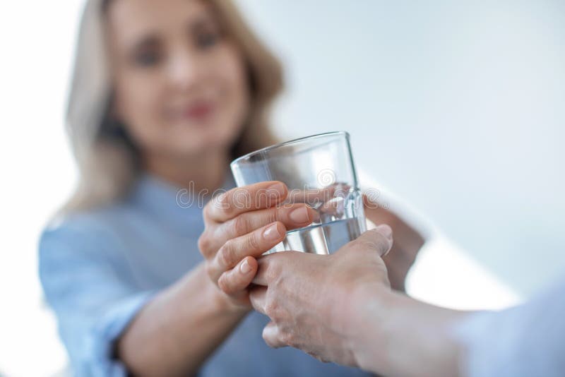 Close-up of female hands giving glass of water to blonde female