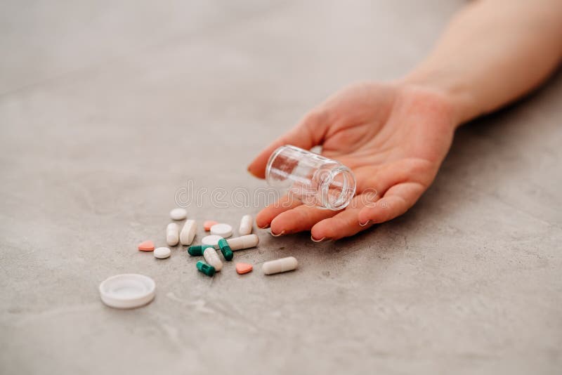 Taking medicine overdose and lying on floor with pills.