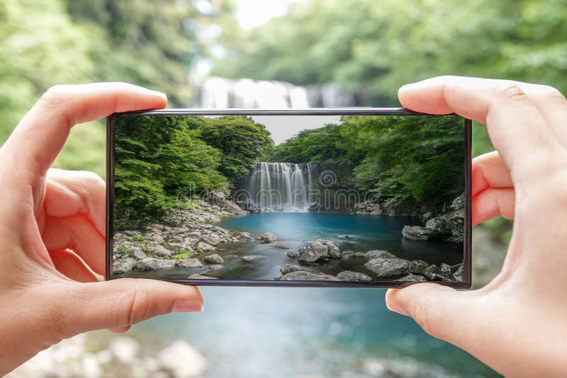 Taking Photo of Cheonjeyeon Waterfall on Jeju Island, South Korea with Mobile Phone. Active Tourism in Asia stock photo Taking Photo of Cheonjeyeon Waterfall on Jeju Island, South Korea with Mobile Phone. Active Tourism in Asia stock photo