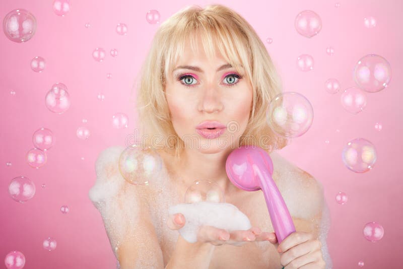 Beautiful happy young girl having a bath blowing bath-foam. Beautiful happy young girl having a bath blowing bath-foam