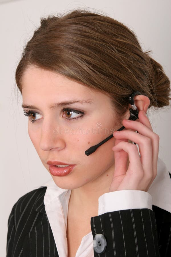Pretty young woman in business attire talking on a headset. Pretty young woman in business attire talking on a headset