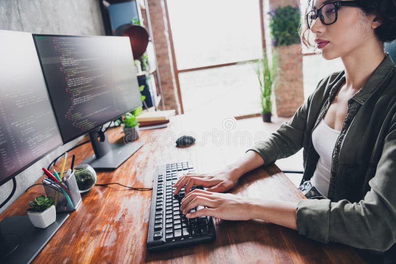 Young female programmer working at a computer desk in a casual home office environment developing software code royalty free stock photo