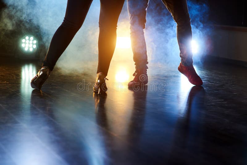 Talentierte Tänzer, die in der Dunkelkammer unter dem Konzertlicht und -rauche durchführen Schöne unmännliche und männliche Beine stockbild