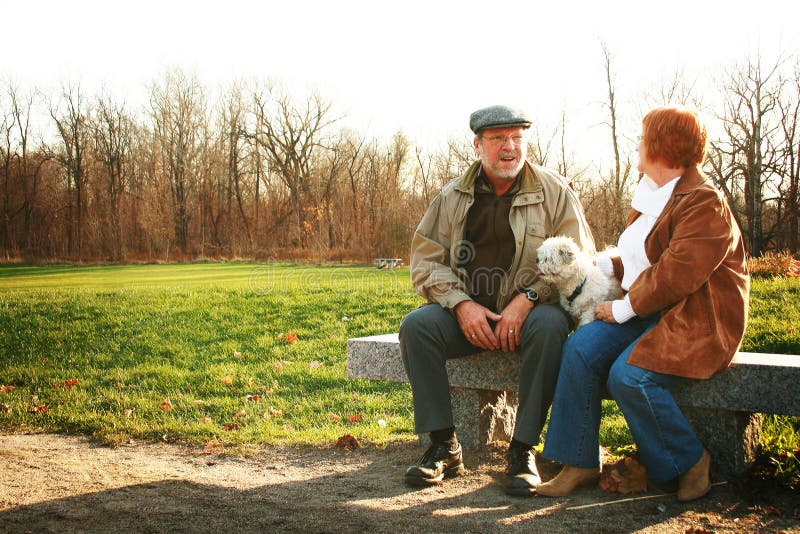 Dôchodcovia pár hovoriť na lavičke s ich psom.