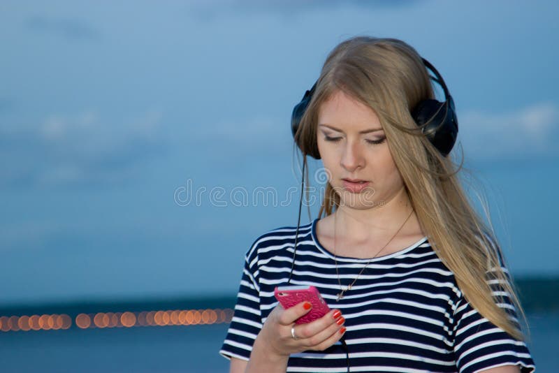 Photo from a series of pictures taken after sunset. The main subject - a beautiful girl, phone and headphones. Photo from a series of pictures taken after sunset. The main subject - a beautiful girl, phone and headphones
