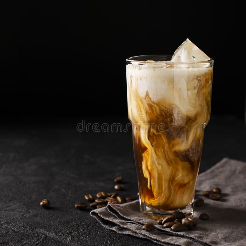 Tall glass cold brew coffee with ice and milk on black or dark b stock photo