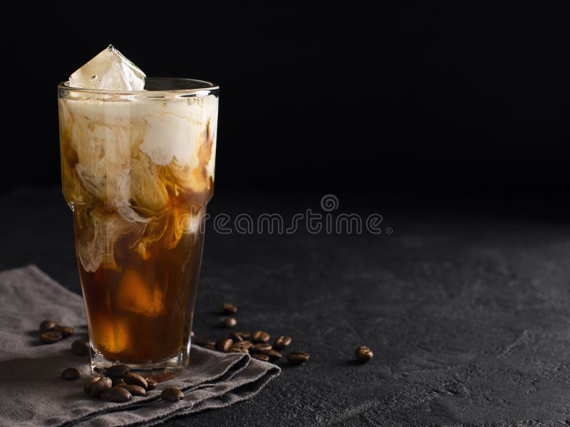 Tall glass cold brew coffee with ice and milk on black or dark b stock photography