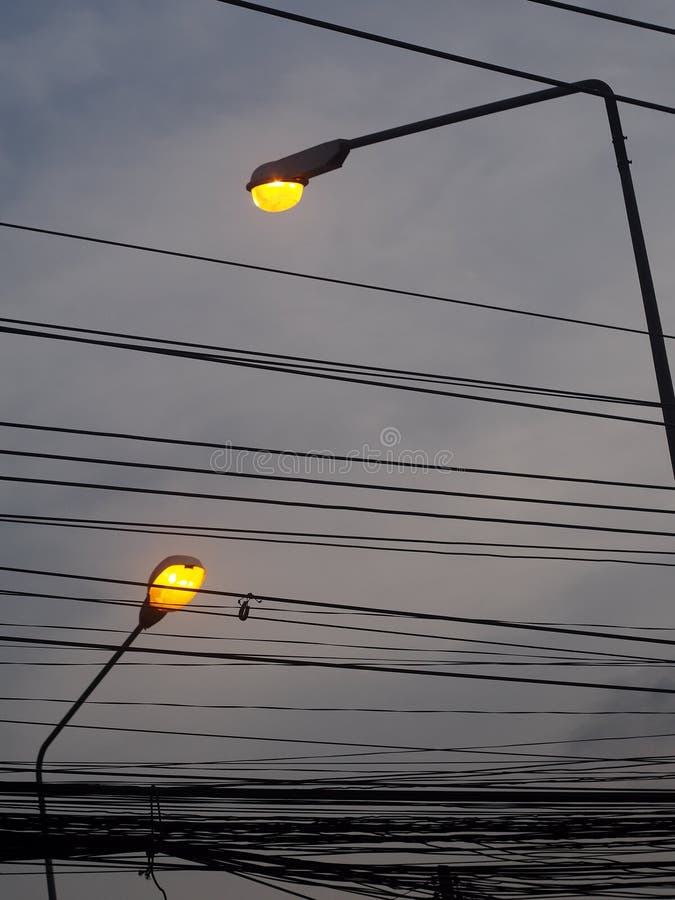 Tall yellow bulb lighting street lamp outdoor silhouette isolated with grey dark cloudy sky