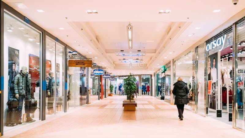 Tallinn, Estonia. Woman walks down hall along with clothing stores in the modern shopping mall Kristiine