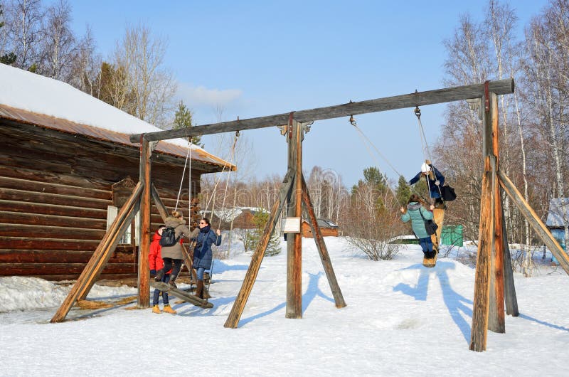 Taltsy, região de Irkutsk, Rússia, março, 02, 2017 O pessoa que monta no russo idoso balança no museu arquitetónico-etnográfico d imagens de stock Taltsy, região de Irkutsk, Rússia, março, 02, 2017 O pessoa que monta no russo idoso balança no museu arquitetónico-etnográfico d imagens de stock
