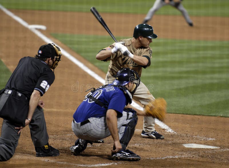 A hitter about to hit a pitch with catcher receiving the ball and umpire in position to make a call about balls and strikes. A hitter about to hit a pitch with catcher receiving the ball and umpire in position to make a call about balls and strikes.