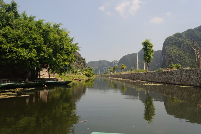 Tam coc, Vietnam; 08 10 2019: Sampan boat-ride, rowed by a villager at Tam Coc , Vietnam : the karst landscape with many vertical sides and covered by much green vegetation. Tam coc, Vietnam; 08 10 2019: Sampan boat-ride, rowed by a villager at Tam Coc , Vietnam : the karst landscape with many vertical sides and covered by much green vegetation.