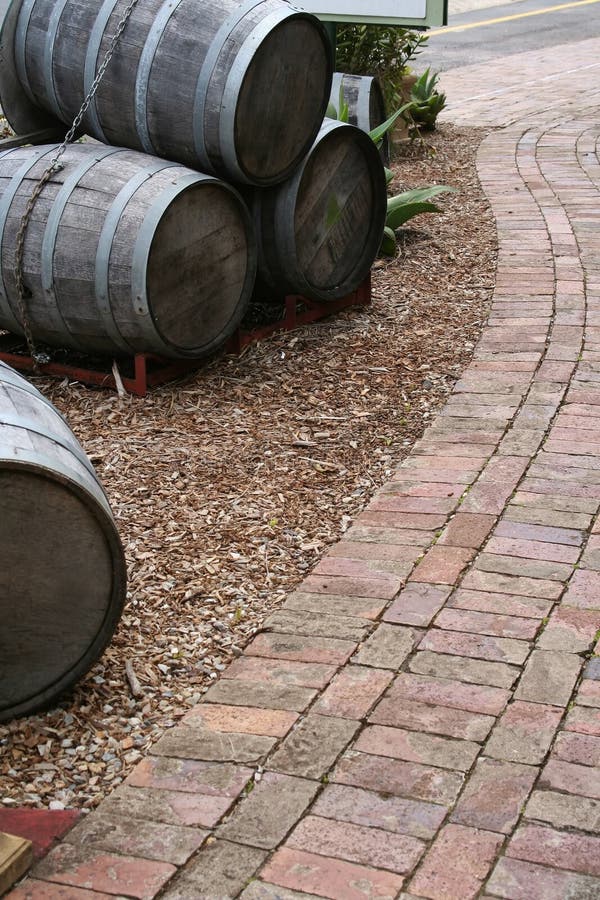 Cropped view of a walking path near a vineyard. Decorative wine casks line the pathway. Cropped view of a walking path near a vineyard. Decorative wine casks line the pathway.