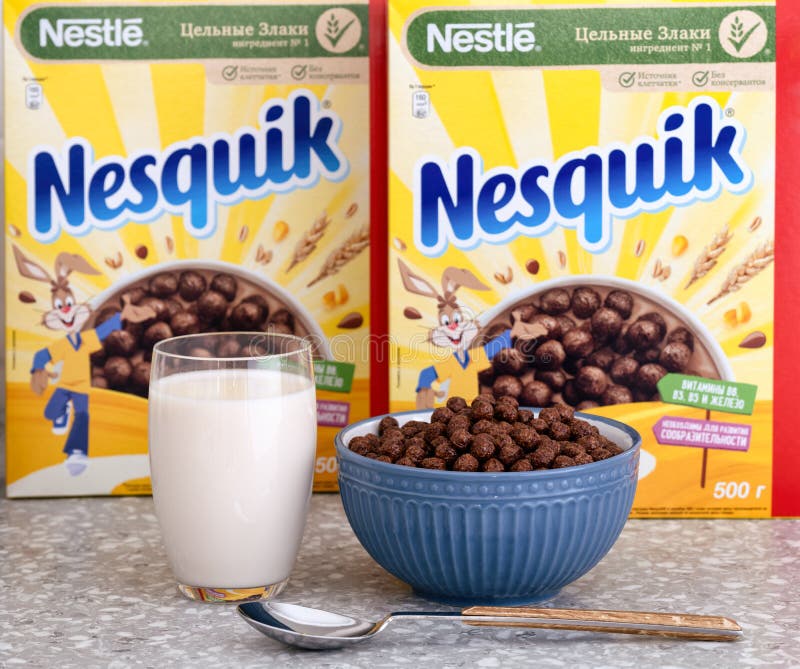 A glass of milk and a bowl of Nestle Chocolate Nesquik cereal against a background of Nestle Chocolate Nesquik cereal boxes