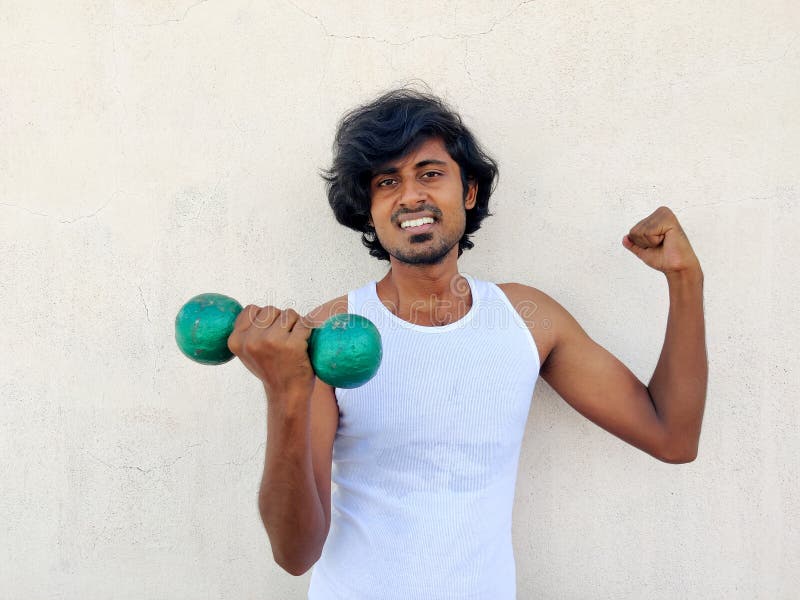 Tamil che tiene in mano dei gusci di una mano e mostra il muscolo bicipite dell'altra mano. concetto di esercizio del corpo magro. immagine stock