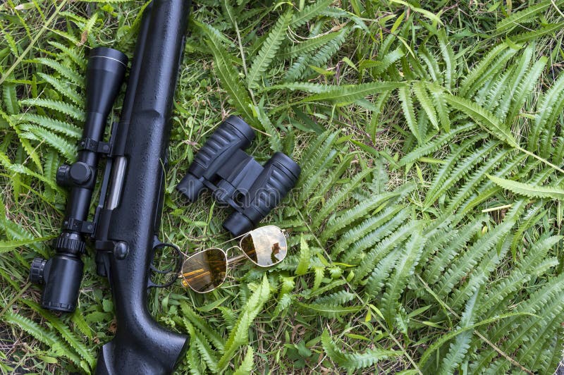 Top view close up rifle and binoculars on grass floor with copy space. Top view close up rifle and binoculars on grass floor with copy space.