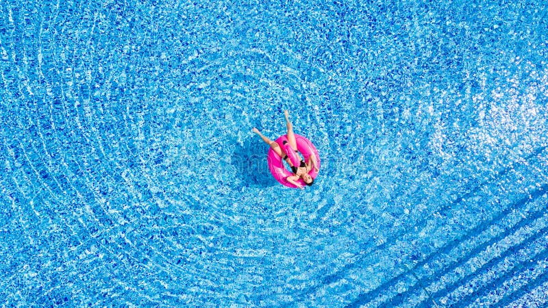 Tan-Mädchen sitzt auf aufblasbaren Matratzenflamingos im Pool von oben stockbilder Tan-Mädchen sitzt auf aufblasbaren Matratzenflamingos im Pool von oben stockbilder