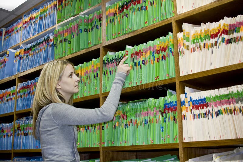 A medical secretary looks up a patients medical records and insurance information. A medical secretary looks up a patients medical records and insurance information