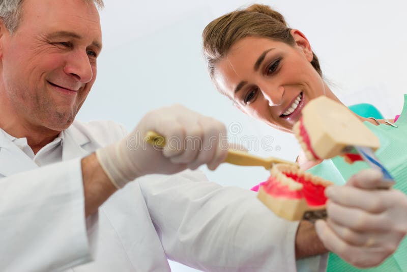 Tandarts die tanden verklaart die aan patiënt borstelen