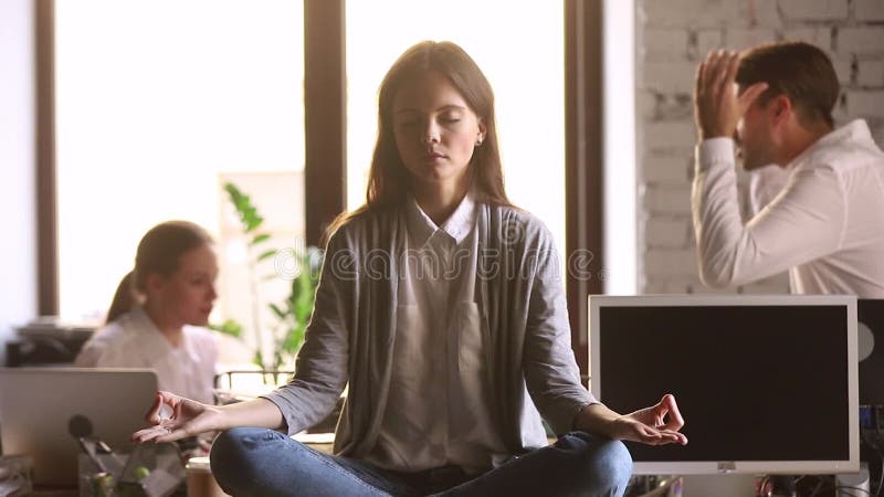 Tandis que des collègues discutant de la femme assise au bureau se concentraient sur la méditation