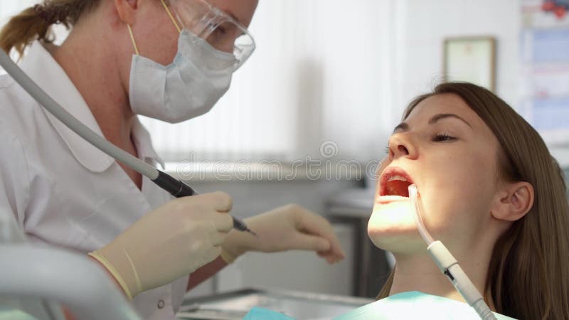 Tandläkare som behandlar tänder till kvinnapatienten i klinik Kvinnlig yrkesmässig doktor på arbete tand- checkup
