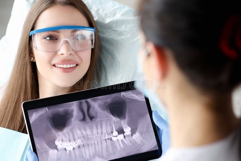 Dentist holding digital tablet with 3D picture of teeth in hands in front of female patient. Dental implantation concept. Dentist holding digital tablet with 3D picture of teeth in hands in front of female patient. Dental implantation concept