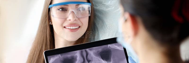 Dentist holding digital tablet with 3D picture of teeth in hands in front of female patient. Dental implantation concept. Dentist holding digital tablet with 3D picture of teeth in hands in front of female patient. Dental implantation concept