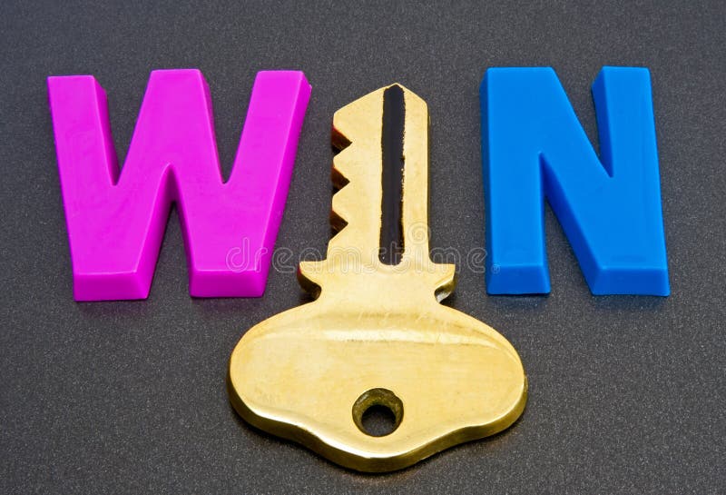 A macro image of the word win in upper case letters but where the letter i is replaced by a gold key. The image is isolated on a dark background. A macro image of the word win in upper case letters but where the letter i is replaced by a gold key. The image is isolated on a dark background.