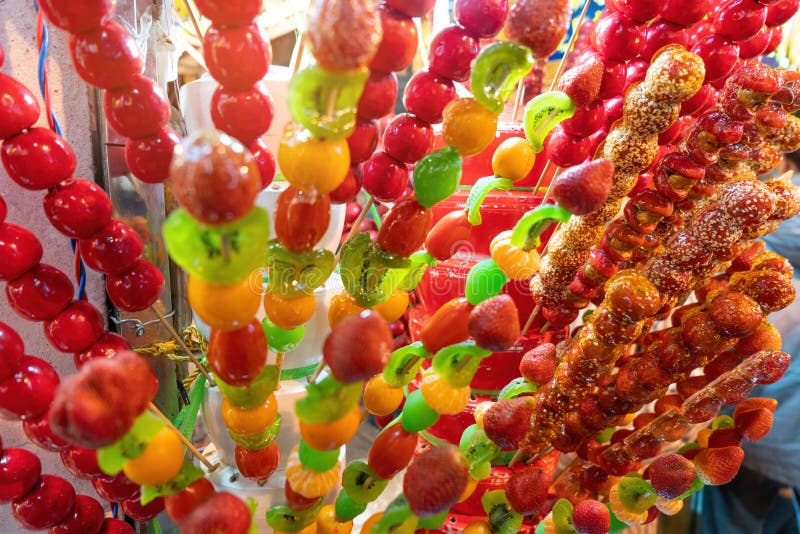 Tanghulu traditional Chinese dessert candied fruit on a wooden stick. Sugar candy Chinese dessert street food