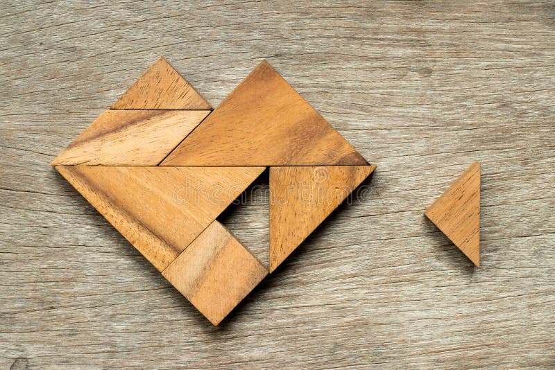 Tangram puzzle in heart shape wait to fulfill with triangle shape on wooden background. Tangram puzzle in heart shape wait to fulfill with triangle shape on wooden background