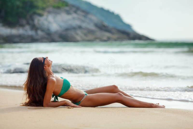 Tanned brunette laying on the beach stock image
