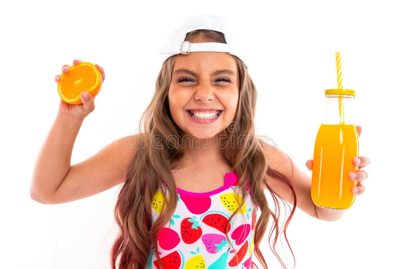 Tanned girl squeezes an orange and holds a glass of juice on a white background royalty free stock photo Tanned girl squeezes an orange and holds a glass of juice on a white background royalty free stock photo