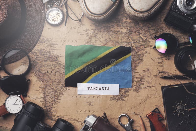 Tanzania Flag Between Traveler`s Accessories on Old Vintage Map. Overhead Shot. Tanzania Flag Between Traveler`s Accessories on Old Vintage Map. Overhead Shot.