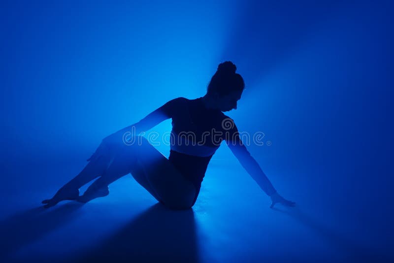 Tanzendes Ballet der Berufsballerina im Scheinwerferrauche. schöne junge Frau, die schwarzen Bodysuit auf Flutlichthintergrund trä lizenzfreie stockfotos