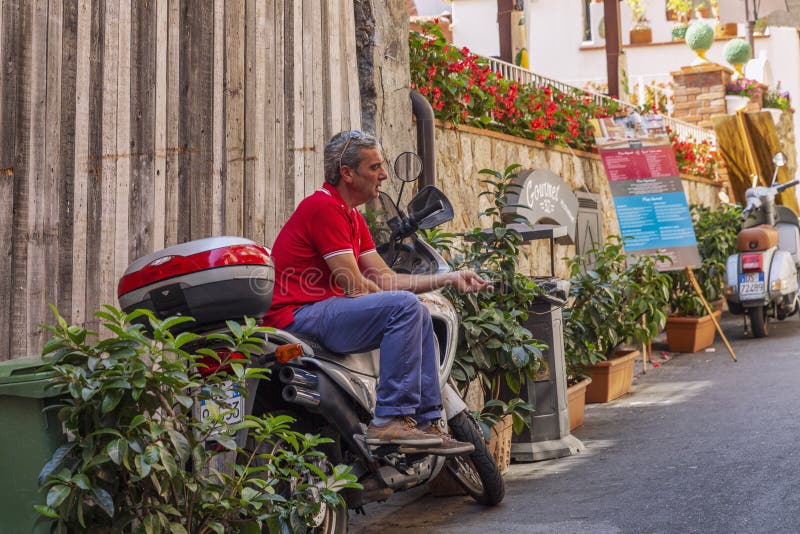 Taormina, Italy, 08/30/2016 a Man Sits on a Scooter in the Shade