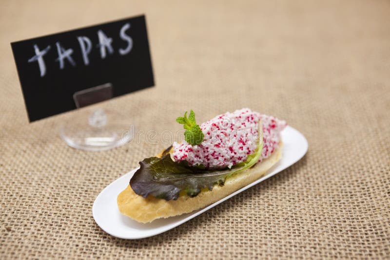 TAPAS-affiche Heerlijke Spaanse tapas met krab tartare met vliegende vissenkuiten en salade op een plak van baguette Een uitsteke stock fotografie TAPAS-affiche Heerlijke Spaanse tapas met krab tartare met vliegende vissenkuiten en salade op een plak van baguette Een uitsteke stock fotografie
