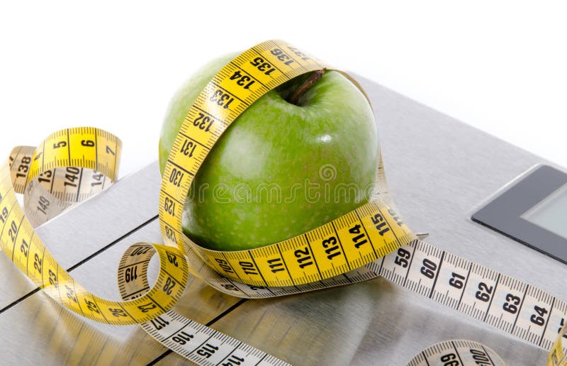 Tape measure around a green apple on a bathroom scales royalty free stock image Tape measure around a green apple on a bathroom scales royalty free stock image