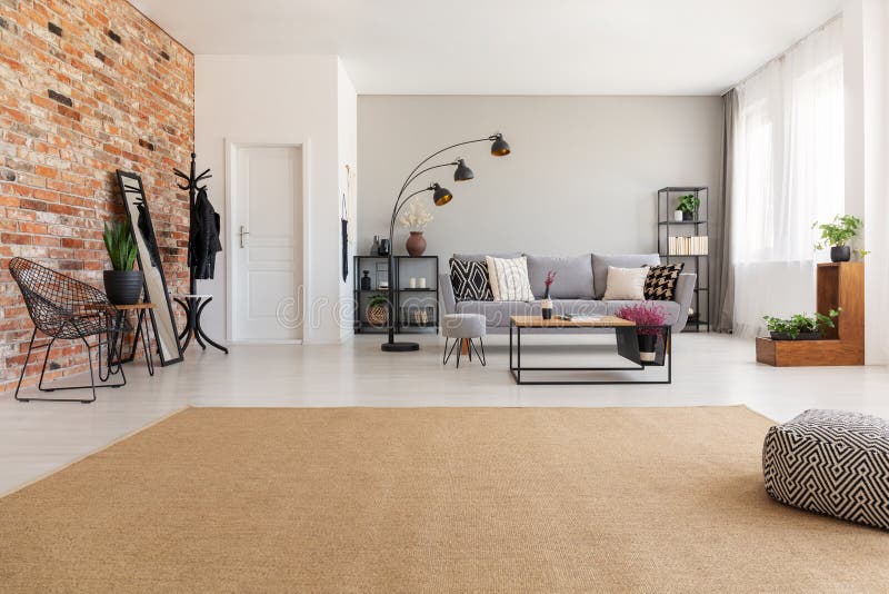 Tapis beige dans le salon moderne intérieur avec le divan gris, lampe noire industrielle en métal, table basse en bois photo stock