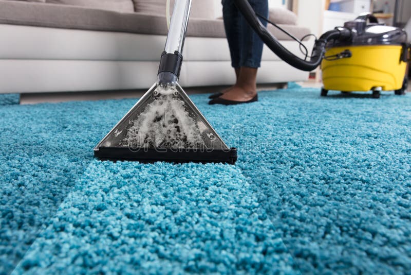 Person Using Vacuum Cleaner For Cleaning Blue Carpet At Home. Person Using Vacuum Cleaner For Cleaning Blue Carpet At Home