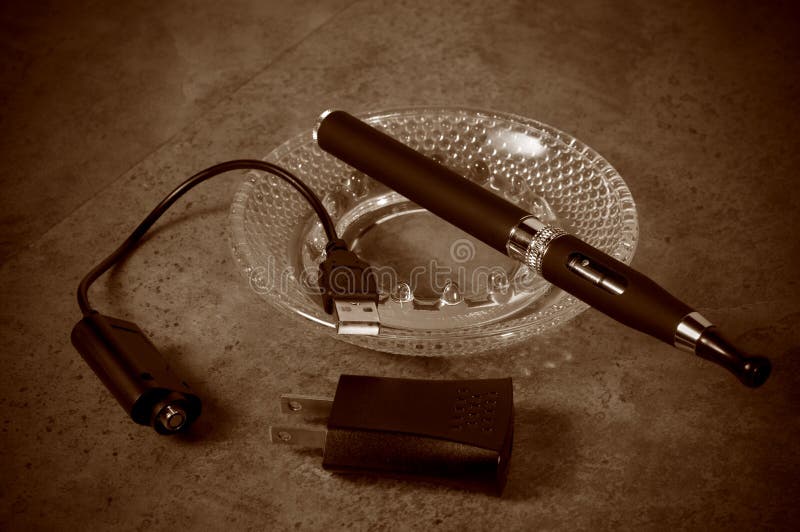 Tappning som ser den elektroniska cigaretten med uppladdaren royaltyfri bild Tappning som ser den elektroniska cigaretten med uppladdaren royaltyfri bild