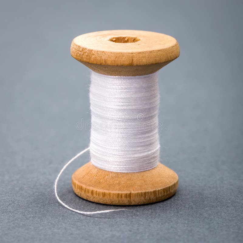 Vintage wooden spool of white sewing thread on gray background. Vintage wooden spool of white sewing thread on gray background