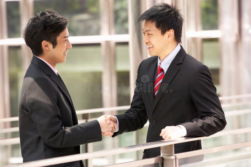 Two Chinese Businessmen Shaking Hands Outside Office. Two Chinese Businessmen Shaking Hands Outside Office