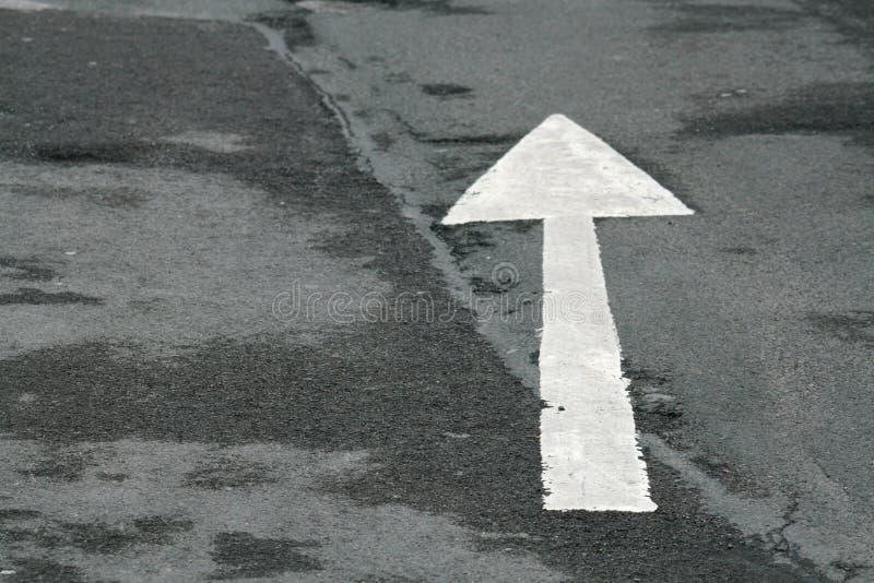 A white arrow painted on damp tarmac. A white arrow painted on damp tarmac